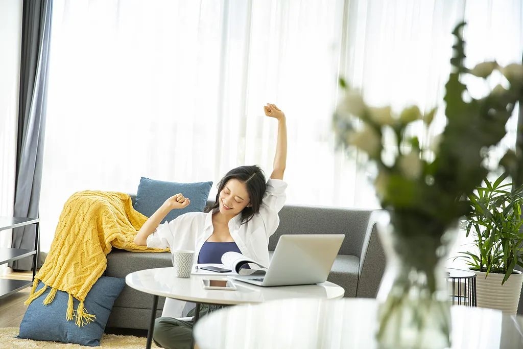 青年女子在客厅居家远程办公放松伸懒腰图片素材