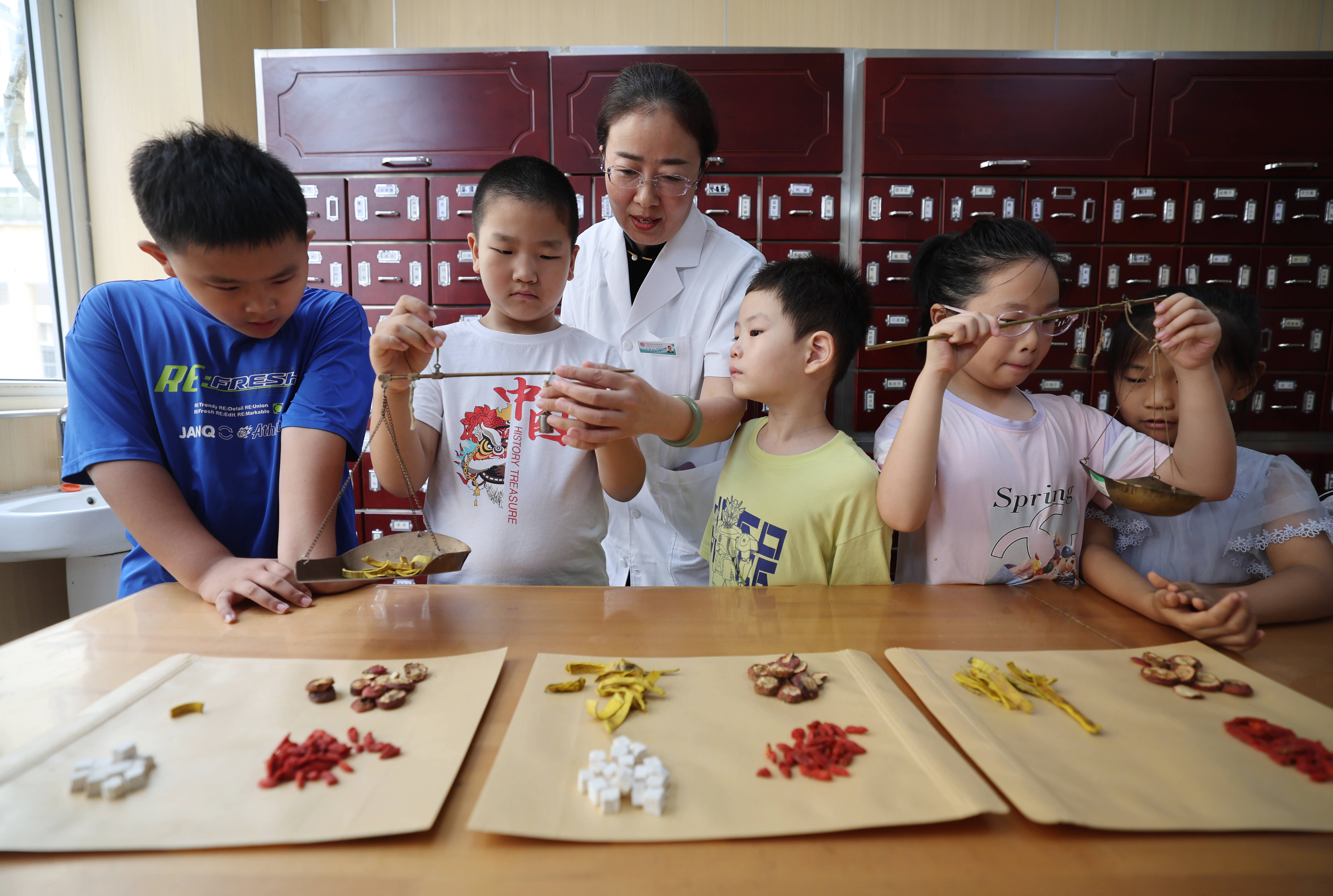 在沂南县妇幼保健院，小学生在中药师的指导下体验抓中草药。