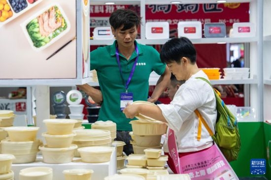 9月19日，在长沙国际会展中心，观众（右）在了解一次性饭盒。